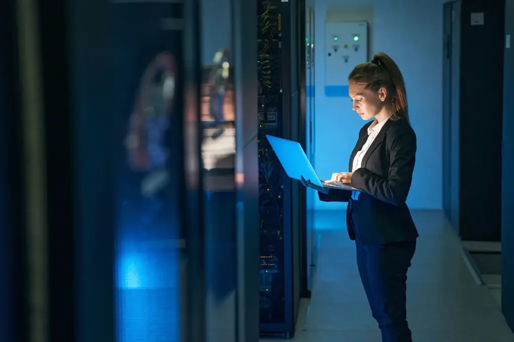 Cloud engineer with a laptop in a data center aisle
