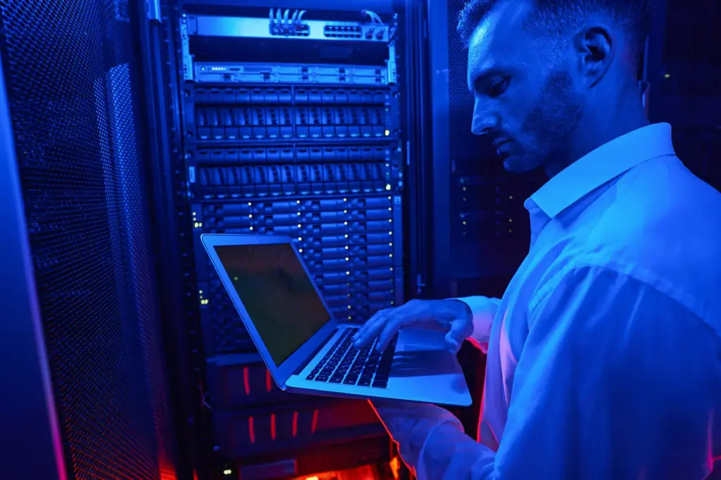 Engineer working on a laptop at a lit server rack