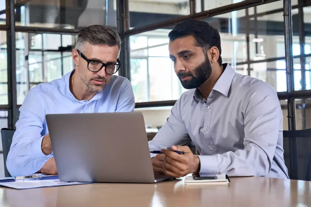 Security expert working with an IT manager at a laptop